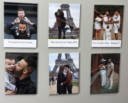 Six custom square photo magnets with white borders are arranged in two rows of three on a light gray wall. The photos show family and couple memories, including the Eiffel Tower, and each print has a caption below it.