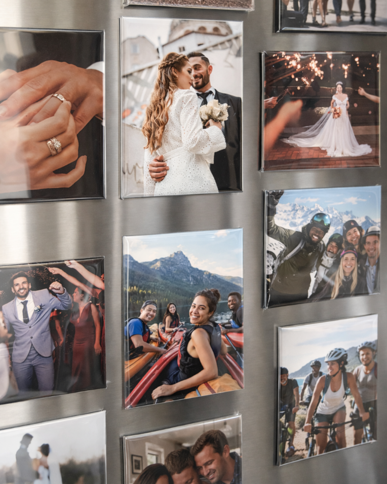Collection of photo magnets on a metallic surface, including a couple, a wedding scene, and various other moments.