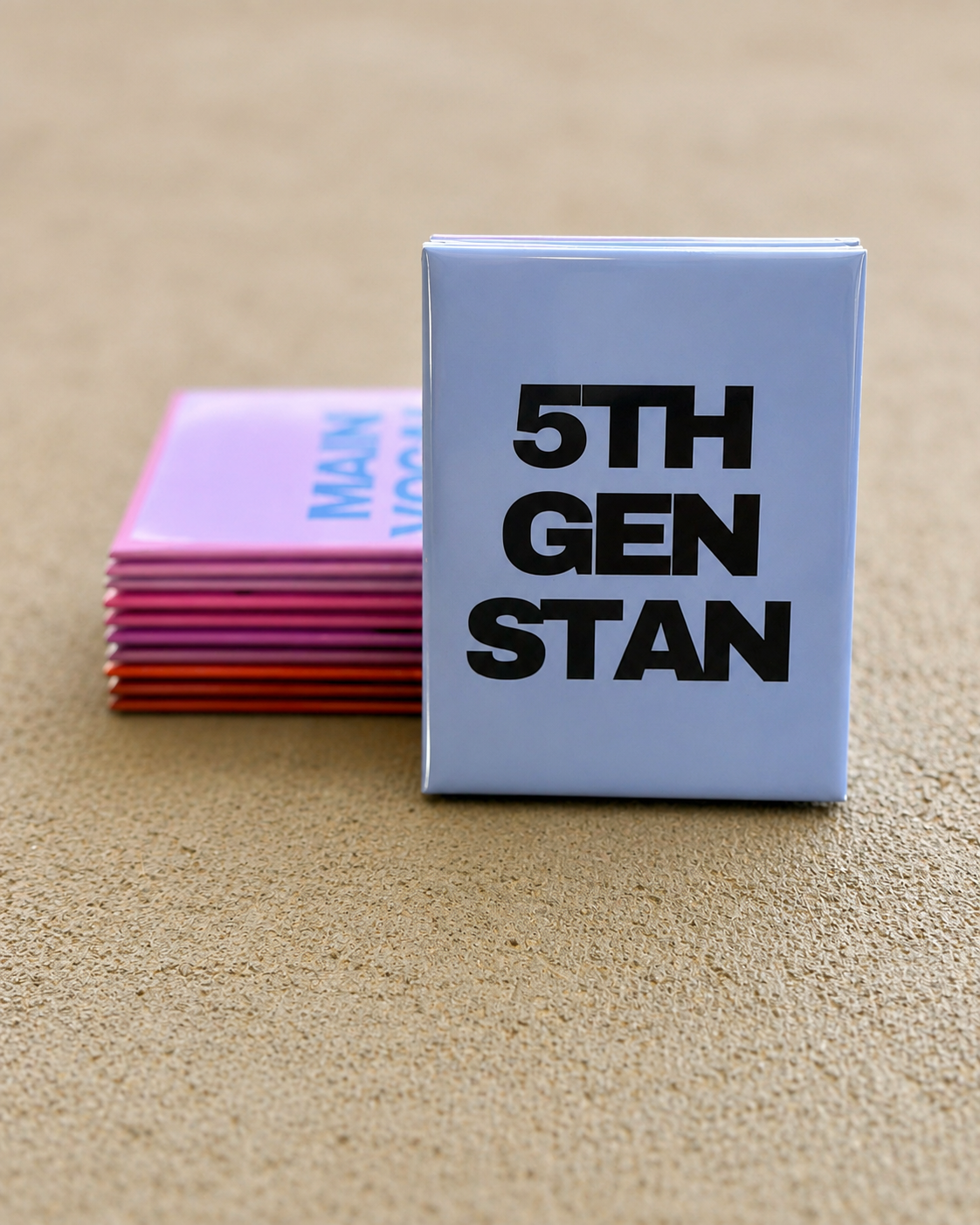 Stack of colorful magnets with a blue magnet labeled '5TH GEN STAN' on a beige surface