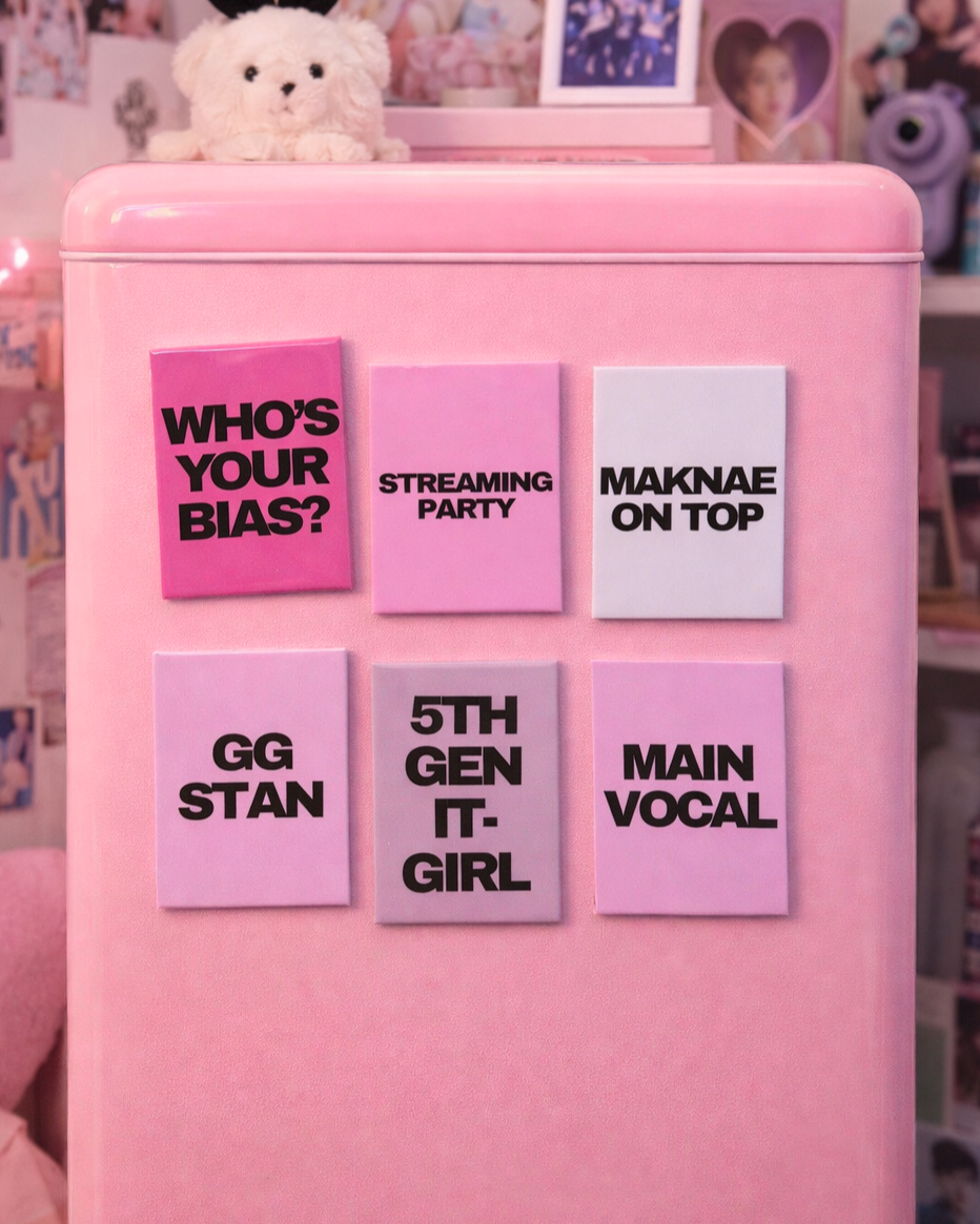 Pink refrigerator with colorful K-POP magnets on a blurred background